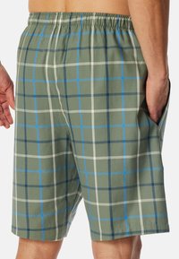 Shorts à carreaux pour hommes verts, avec une taille élastique, des poches latérales et un motif de lignes à carreaux blanches et bleues.