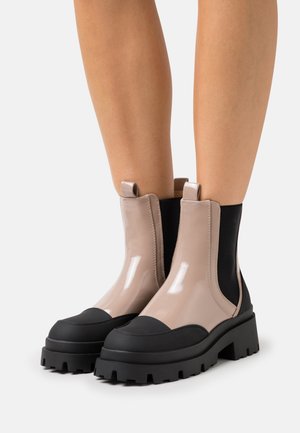 Masywne botki na kostkę z błyszczącej, cielistej skóry z czarnymi akcentami, elastycznymi bocznymi panelami i grubą, żebrowaną czarną podeszwą.