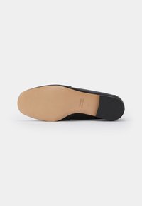 Semelle de chaussure en cuir noir avec dessous couleur beige clair, bout carré, et marquage de taille 37, photographiée sur fond blanc.
