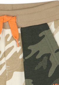 Pantaloni corte con motivo mimetico, dotati di una vita a coste color sabbia, cordino arancione e tessuto in tonalità di verde, beige e bianco sporco.
