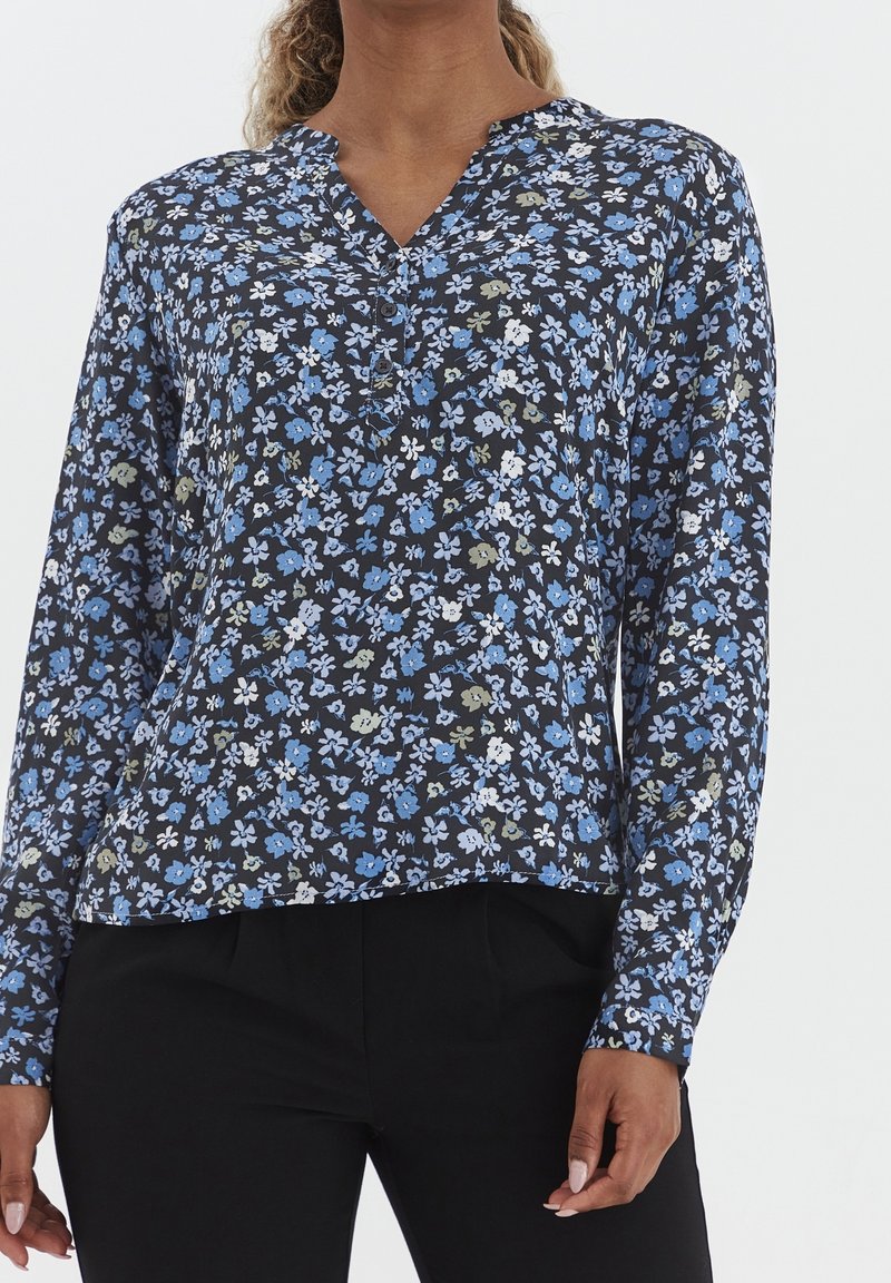 Långärmad blus i mörk marinblått tyg, med ett blommönster i blått, vitt och grönt. Knappstängd halsringning, avslappnad passform.