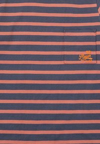 Camisa de manga corta azul marino con rayas corales horizontales. Cuenta con un pequeño bolsillo en el pecho y texto bordado en naranja en el bolsillo.