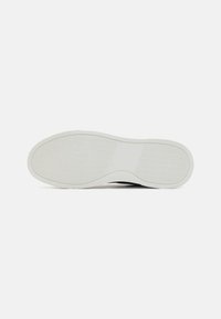 Semelle de chaussure avec une surface en caoutchouc blanc texturé, présentant un motif en vagues et un design incurvé. Robuste et plate pour une meilleure adhérence.