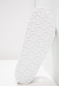 Sole di scarpa bianca con un design testurizzato e motivi circolari, con la parola "Birki" in rilievo, angolata su uno sfondo chiaro.