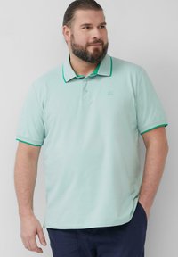Licht groene polo met een kraag en groene accenten. Korte mouwen, zachte textuur, met een klein logo op de borst. Casual fit.