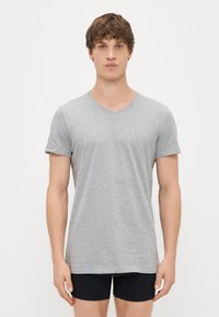 Γκρίζο κοντομάνικο μπλουζάκι V-neck σε μαλακό μείγμα βαμβακιού, με εφαρμοστή γραμμή και απλή υφή. Συνδυασμένο με μαύρα σορτς.