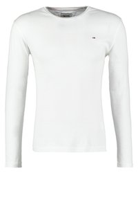 Camiseta de manga larga blanca de tela de algodón con cuello redondo y pequeño logo bordado en el pecho. Textura suave, diseño simple.