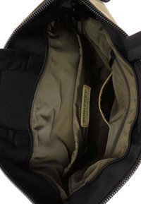 Bolso negro abierto que muestra un interior beige espacioso con un bolsillo con cremallera y una etiqueta de marca "Surifrey Green Label".