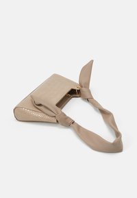 Beige keinonahkainen käsilaukku, jossa on teksturoidulla krokotiilikuviolla ja solmittu kangasolkaimen lisäksi kultainen metallikoriste.