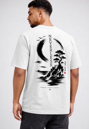 Man wearing white t-shirt with black Japanese-style design of tree on rocky island, crescent moon, birds, and text "NEVERLESS" vertically.