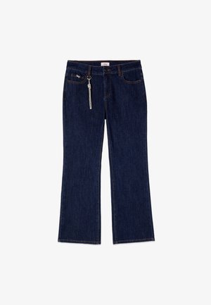 Jean en denim bleu foncé avec jambes droites, bouton et fermeture éclair à l’avant, cinq poches et un porte-clés en corde blanche nouée sur la boucle de ceinture droite.