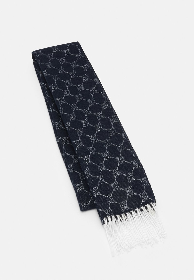 Écharpe bleu marine pliée, présentant un motif circulaire gris clair et des extrémités blanches à franges, posée sur une surface blanche.