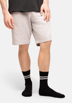 Shorts di cotone grigio chiaro con fascia elastica in vita, di lunghezza sopra il ginocchio, abbinati a calzini neri a crew con due strisce bianche.