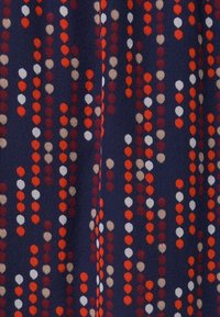 Tissu avec un fond marin présentant des colonnes verticales de points arrondis en rouge, orange, beige et blanc. Texture douce, poids moyen.