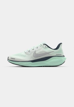 Zapatilla de running de malla verde clara con un swoosh gris, acentos azul oscuro y una suela texturizada. Cuenta con una entresuela acolchada y cierre con cordones.