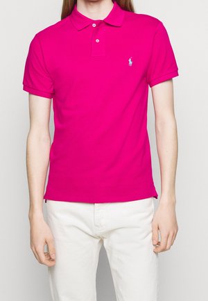 Polo fucsia de algodón. Cuenta con cuello clásico, mangas cortas, tapeta de dos botones y un pequeño logo en el pecho izquierdo.