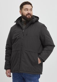 Sort hættetrøje med lynlås foran, elastiske snore og et to-farvet design. Har sidelommer og en afslappet pasform.