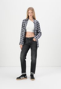 Tumed ja valged ruudulised flanellpait, lühike valge topp, tumehallad teksad ja mustad sneakerid valgete triipudega ning kummitaldadega.