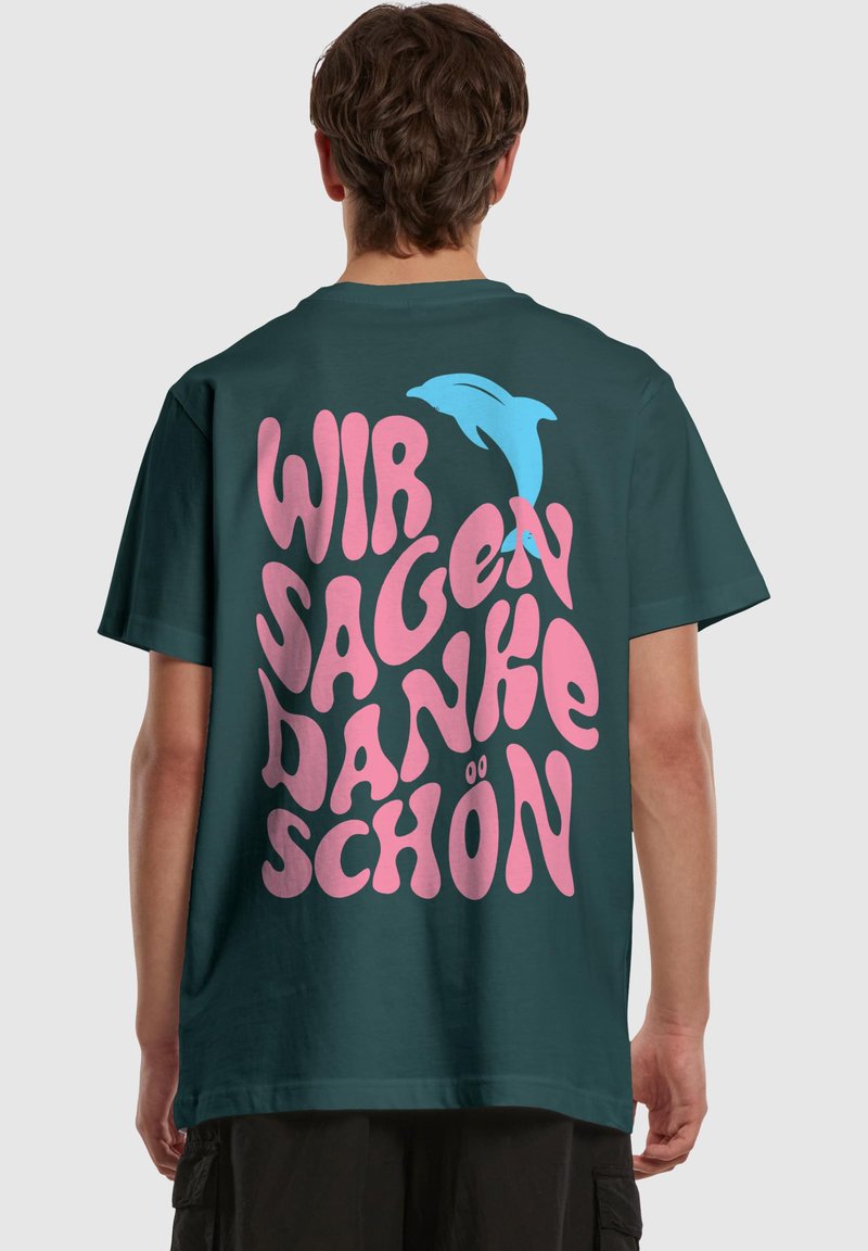 Dark green oversized t-shirt featuring playful pink and blue text and dolphin graphic on the back. Short sleeves and classic crew neck.