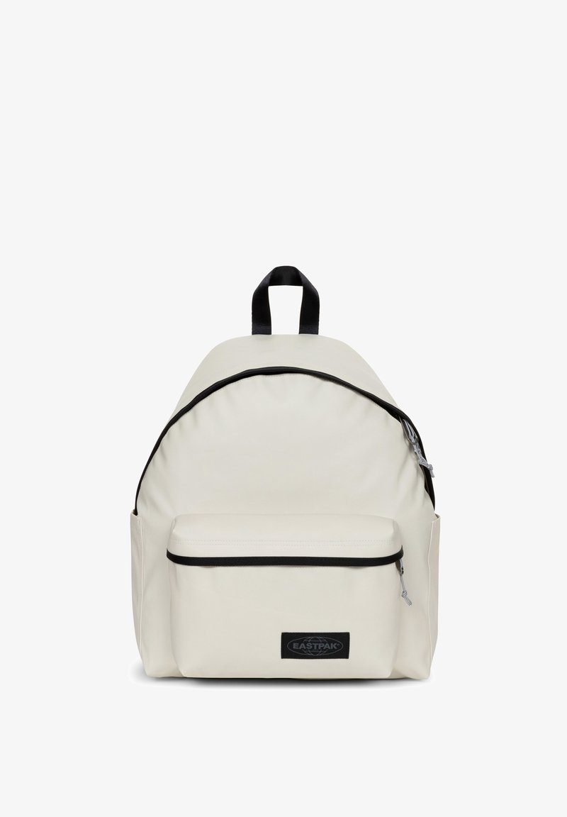 Sac à dos en tissu couleur crème de forme arrondie, doté d'une poche zippée à l'avant et d'accents noirs autour des bords et du logo.