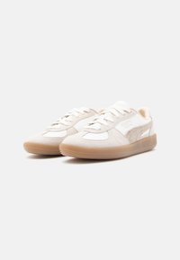 Sneakers bianchi con accenti beige, materiali in pelle scamosciata e pelle testurizzati, punta rotonda, design con lacci e suola in gomma.