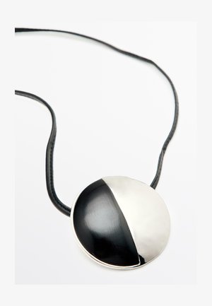 Round pendant necklace with a black and silver half design, featuring a leather cord. Smooth metal and textured surface contrast.