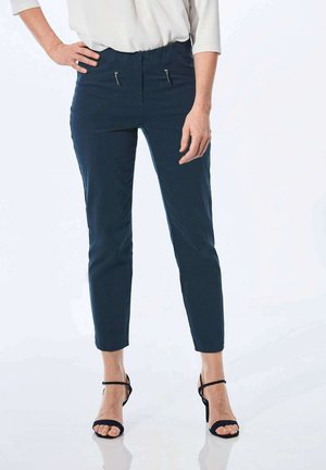 Marineblauwe getailleerde broek met ritszakken, cropped lengte en een soepele textuur, gecombineerd met zwarte bandjeshakken.