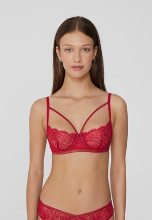 Red lace bra featuring a sheer design, dual strap detail, and a decorative scalloped edge along the neckline and underband.