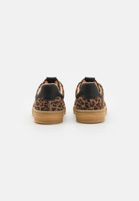 Løveprint sneakers med sorte detaljer, med en blød ruskindsoberdel, gummigummisål og en hælflap for nem påklædning.