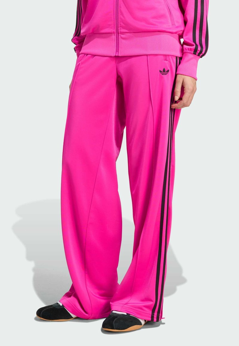 Roze polyester trainingsbroek met zwarte zijkanten en een klein logo. Losse pasvorm met een gladde textuur, geschikt voor sport of casual draag.