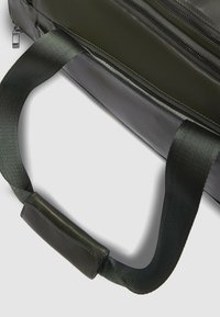 Borsa verde scuro dal design elegante, con superficie testurizzata, chiusura a zip e manico imbottito in tessuto per il massimo comfort.