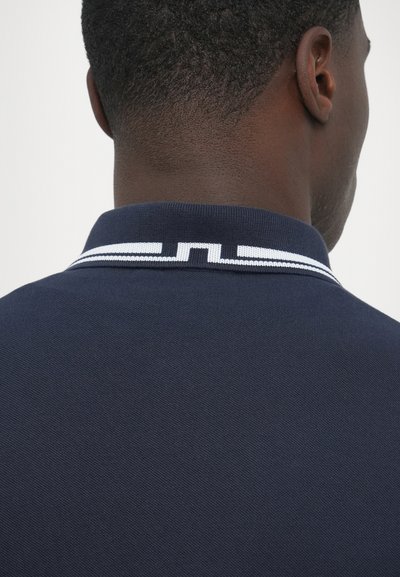 Námornícka polokošeľa s textúrovanou tkaninou, s bielym pásikavým golierom a vyšívaným detailom na chrbte.