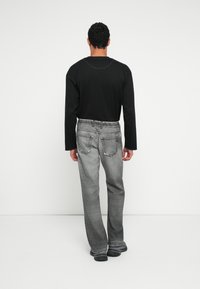 Μαύρο πουκάμισο με μακριά μανίκια, συνδυασμένο με γκρι τζιν με ελαφρώς φθαρμένο στυλ, που διαθέτει αντίθετη ραφή και πέντε τσέπες.