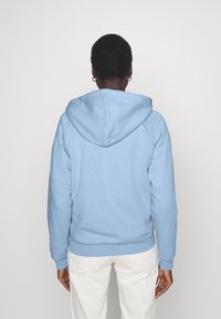 Felpa con cappuccio azzurro chiaro dal tocco morbido. Presenta un cappuccio con cordino, polsini a costine e una vestibilità comoda. Design semplice senza motivi.