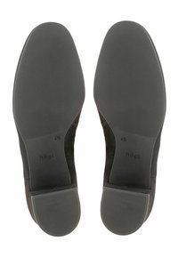Zapatos de ante negros con suelas de goma, con un acabado suave y un logotipo de la marca en relieve. La suela tiene un patrón de agarre texturizado para mayor tracción.