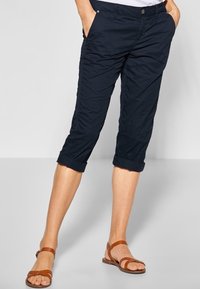 Námořnické capri kalhoty s uvolněným střihem, ohrnutými lemy a bočními kapsami. Vyrobené z lehkého, texturovaného materiálu, zakončené zapínáním na knoflík.