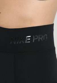 Leggings neri Nike Pro a vita alta con una cintura elastica che presenta un logo lucido. Tessuto morbido, elastico e aderente.