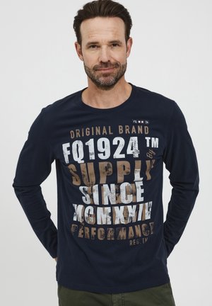 Navy long-sleeve t-shirt made of cotton featuring large contrasting text and logo graphics in white and brown. Round neckline, casual fit.