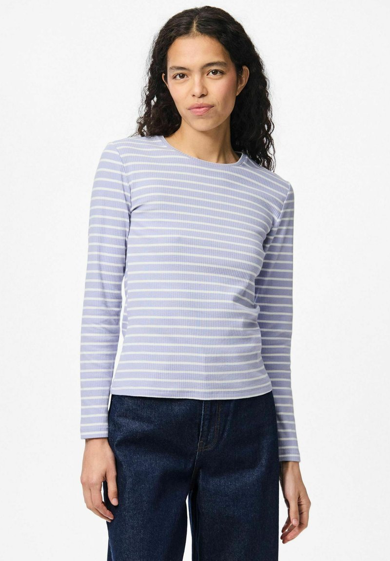 Top de manga larga de color púrpura claro con finas rayas blancas; textura acanalada; escote redondo; combinado con pantalones de mezclilla oscuros.