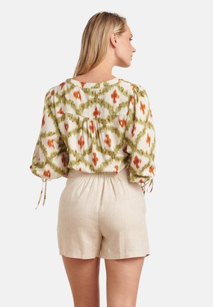 Vloeiende blouse met een meerkleurig abstract patroon in crème, groen en oranje. Gecombineerd met beige linnen shorts met een elastische taille.