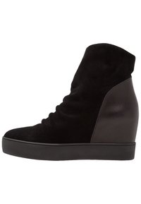 Bota de tobillo negra con cuña, hecha de gamuza y cuero, que presenta una textura recogida en la parte superior y un tacón liso y brillante.