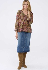 Bruine paisley blouse met een V-hals en klokmouwen, gecombineerd met een denim midirok en bruin suède laarzen tot de knie.