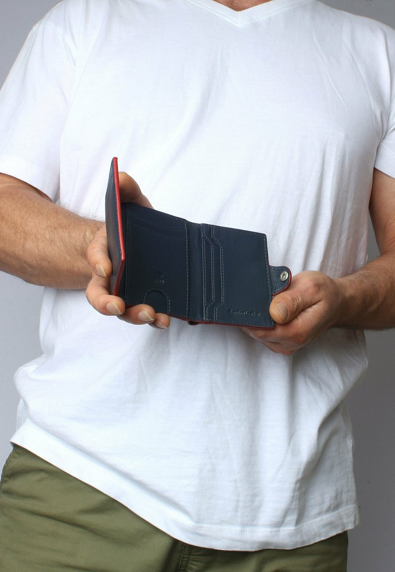 Navy leather wallet with red accents, featuring card slots, a coin pocket, and contrasting stitching. Held open in a hand.