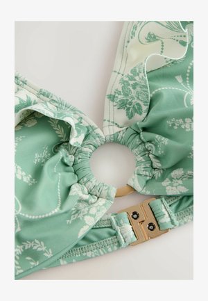Zelený bikiny top s kvetinovým vzorom, volánkovou tkaninou, zlatým kovovým zapínaním a kruhovým stredovým otvorom. Mäkký elastický materiál.