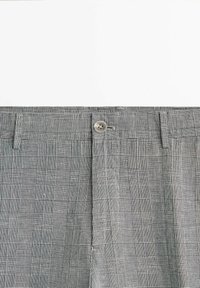 Pantaloni a quadri grigi e bianchi con chiusura a bottone, davanti piatto e texture liscia. Il tessuto presenta un motivo a griglia con variazioni nello spessore delle linee.