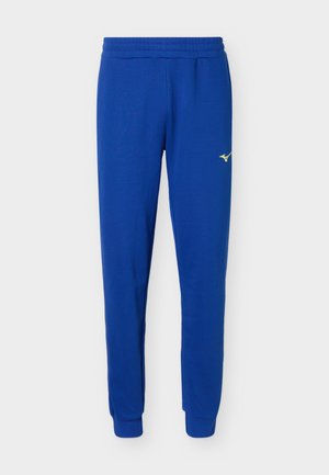 Μπλε φόρμα με ελαστική μέση και μανσέτες, με μικρό κίτρινο λογότυπο στο άνω μέρος του μηρού.