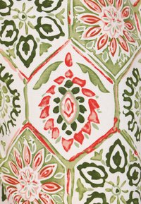 Tessuto colorato con un motivo esagonale e design floreali in rosso, verde e rosa pallido su uno sfondo bianco.