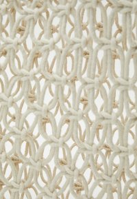 Béžová tkanina s pleteným vzorem, který obsahuje proplétané uzly a měkkou texturu. Design vytváří průsvitný efekt.