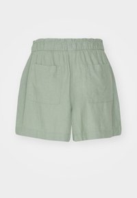 Light green linen shorts with an elastic waistband, featuring two front pockets and a loose fit, textured fabric with a subtle weave.