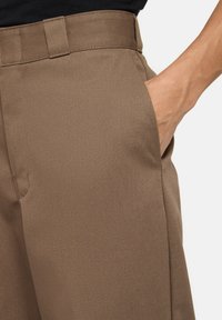 Bruine op maat gemaakte broek van gestructureerde stof, met zijzakken en een soepele tailleband. De pasvorm is recht met een nette afwerking.